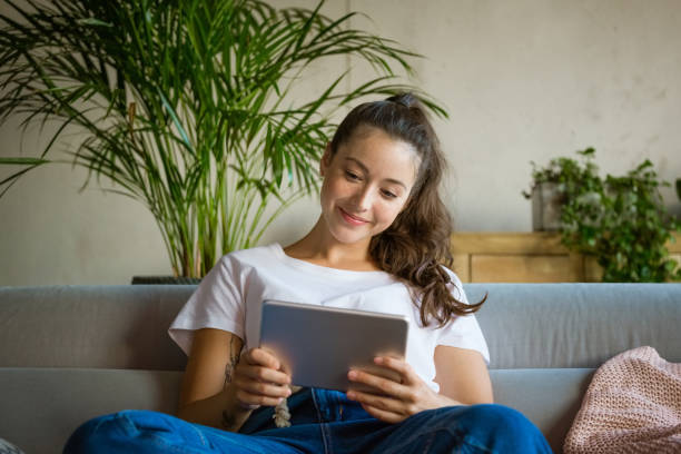 istock Cheerful young woman using digital tablet at home 1330965161