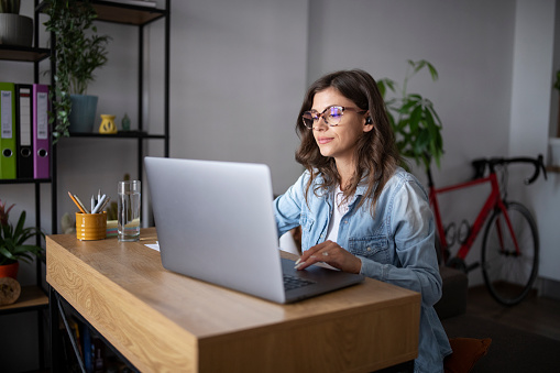 Business woman using a laptop for work in living room