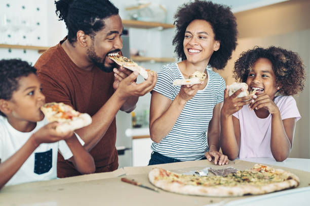 집에서 피자를 먹고 있는 두 자녀를 둔 가족 - pizza eating african descent lunch 뉴스 사진 이미지