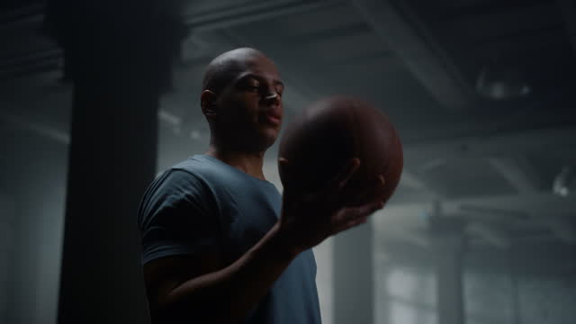 Portrait of serious basketball player spinning basketball ball on finger in gym