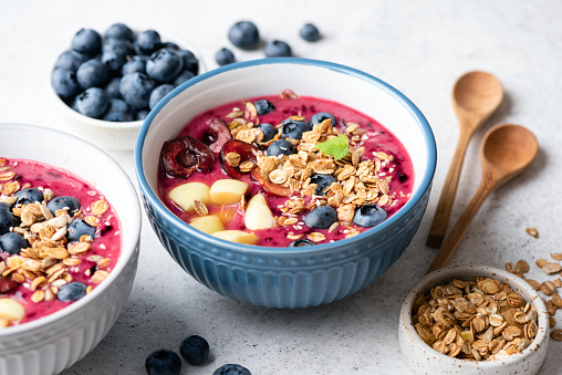 Healthy superfood blueberry smoothie bowl with granola and various berries toppings