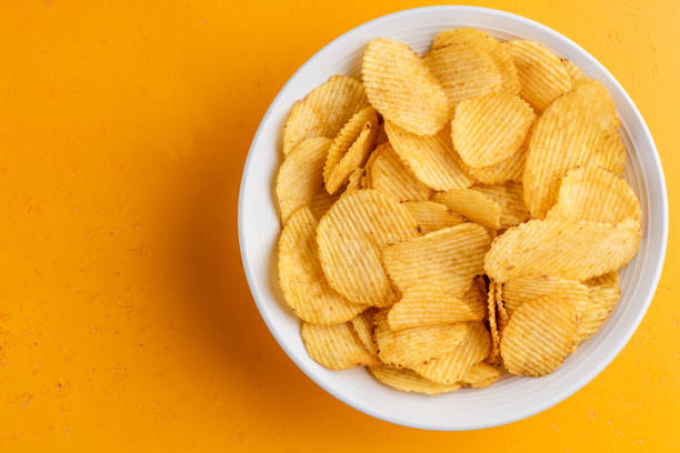 istock Potato chips in bowl on yellow background 1330969966