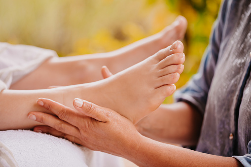 Couple indulges in blissful foot massage at luxurious spa salon for reflexology therapy in gentle day light ambiance resort or hotel foot spa. Quiescent