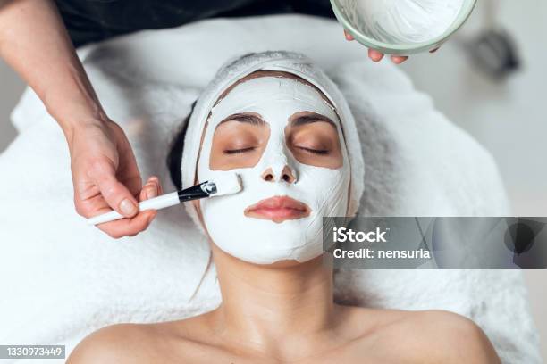 Cosmetologist Applying The Alginates Facial Mask To Woman While Lying On A Stretcher In The Spa Center Stock Photo - Download Image Now
