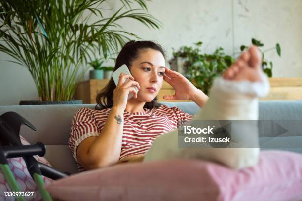 Sad Young Woman With Broken Leg On Phone Stock Photo - Download Image Now - Broken Leg, Women, One Woman Only