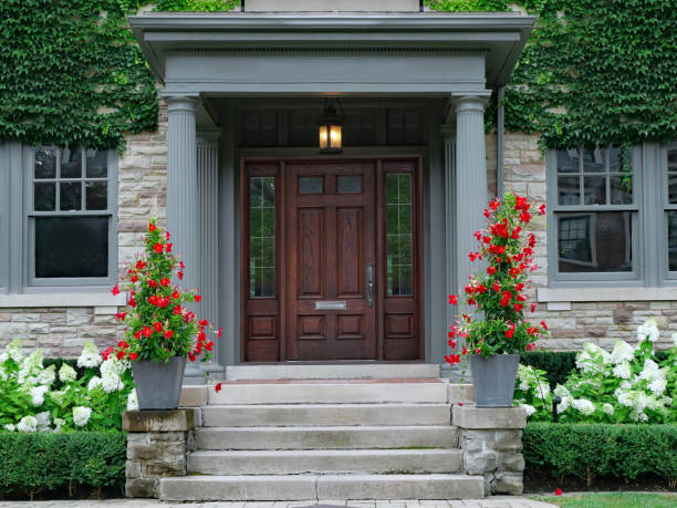 House with elegant wood grain door, surrounded by ivy and  red amaryllis and white hydrangea flowers stock photo