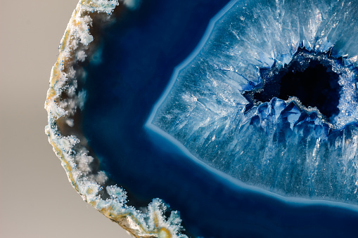 Macro details of a blue agate mineral on reflective surface. Agate has a typical zoned structure and is visible even to the naked eye.