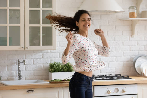 istock Active young hispanic lady jump dance at light modern kitchen 1330975050