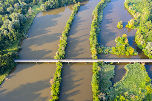 Aerial view of a footbridge over the river and flooded green areas.