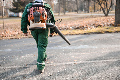 Male Park Worker Carrying Leaf Blowing Machine On Back
