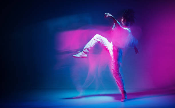 istock Dancing sportive female in colorful neon light. Expressive contemporary dance. Studio photography with long exposure 1330979222