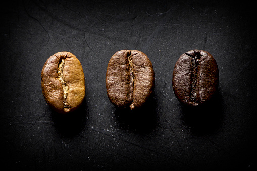 3 different roast coffee beans on a textured black surface