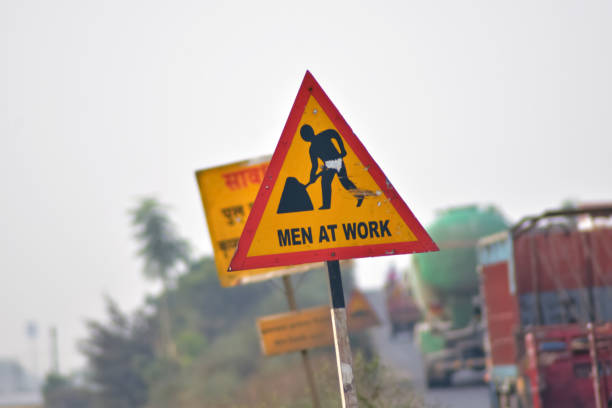 A closeup shot of a road sign with men at work on it
