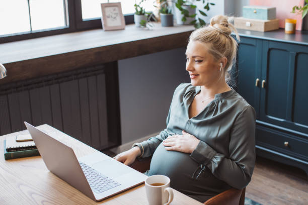 istock Pregnant woman at office working 1330984211