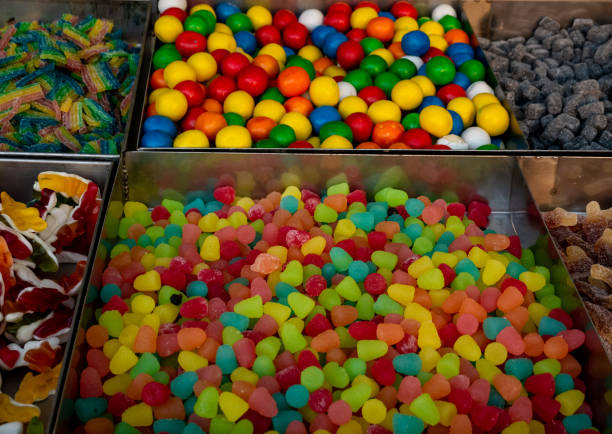 Various types of colorful candies with different flavors for sale at a market counter