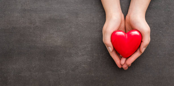 the woman is holding a red heart. - schenking stockfoto's en -beelden