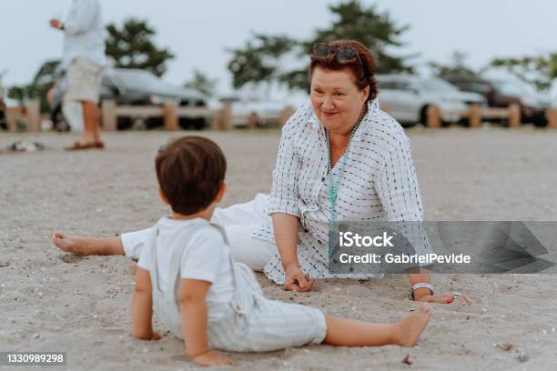 Grandmother Playing With Her Grandson On The Beach Stock Photo - Download Image Now - Aunt, Uncle, 2-3 Years