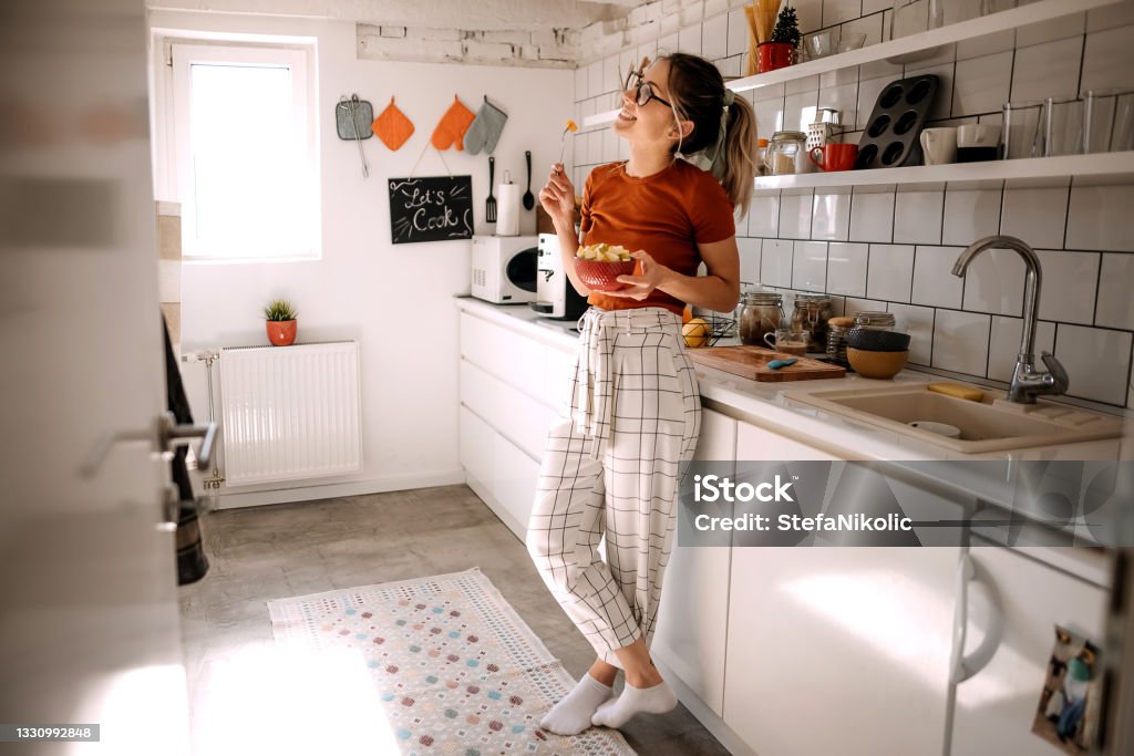 Fresh and healthy Young woman eating fruit salad in the kitchen Banana Stock Photo