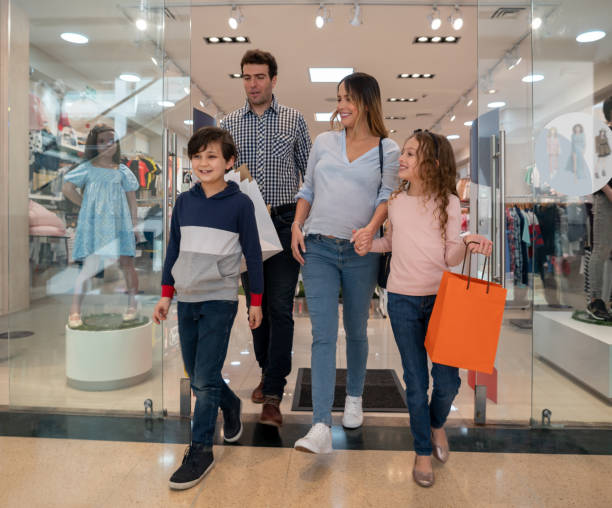 happy family buying clothes for the kids at the shopping center - boutique shopping retail mother imagens e fotografias de stock
