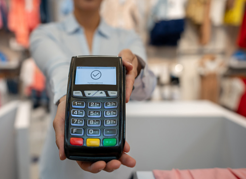Close-up on a EFTPOS machine while paying by card at a clothing store - shopping concepts