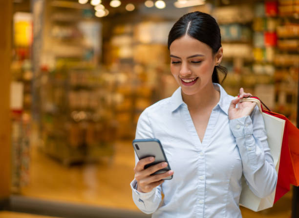 istock Woman using app on her cell phone while shopping at the mall 1330995627