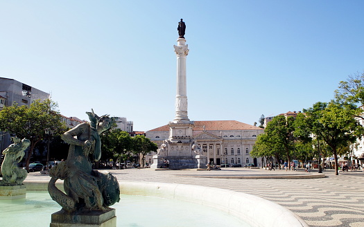 Sculptures of the fountain in the Rossio square, D. Pedro IV Column in the background, monument to the King of Portugal, erected in 1870, Lisbon, Portugal