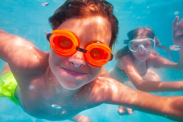 istock Boy in orange glasses dive underwater with friends 1330997124