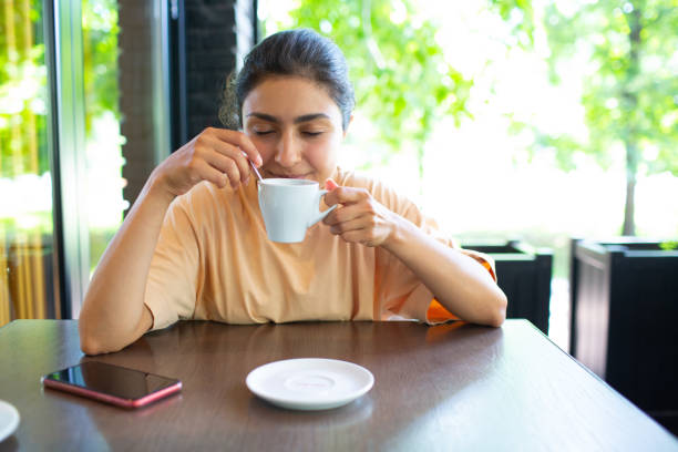 istock Smiling lovely young woman drinking coffee outside 1330997395