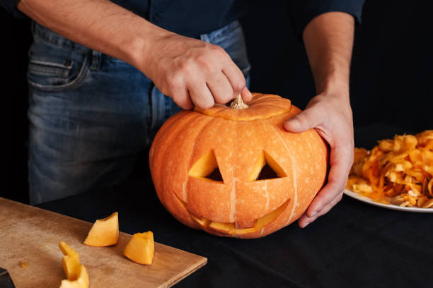 istock man makes an orange pumpkin for Halloween 1331007683