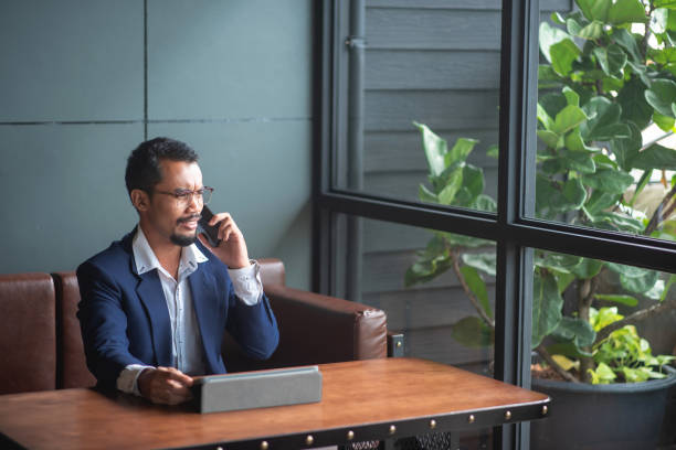 istock Young handsome businessman wears glasses and works on touchpad while sitting on sofa in office. 1331009521