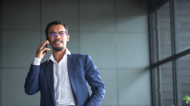 istock Young handsome businessman wears glasses and works on touchpad while sitting on sofa in office. 1331009532
