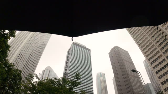 Looking up at a skyscraper through an umbrella on a rainy day