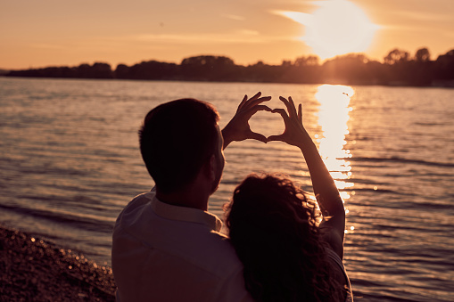Couple hanging out by the river and holding a heart