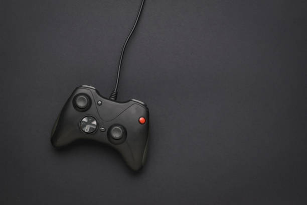 istock A black game console with a wire on a black background. Flat lay. 1331015090
