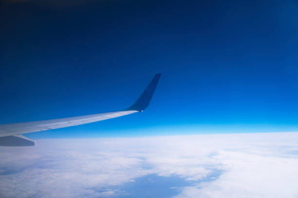 Aircraft wing above the clouds in flight at 10000 meter altitude.