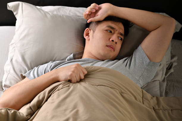 istock Depressed young Asian man lying in bed cannot sleep from insomnia 1331018591