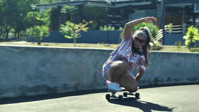 Happiness of senior sporty woman latin american and hispanic ethnicity wearing sunglasses and gray-haired age 53 yearold playing skateboard on a sunny day. Seniors in Sport concept.