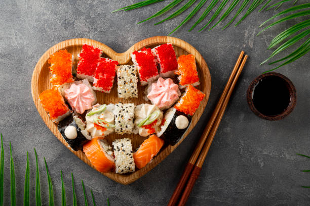 Japanese rolls in heart shaped plate on gray concrete background top view