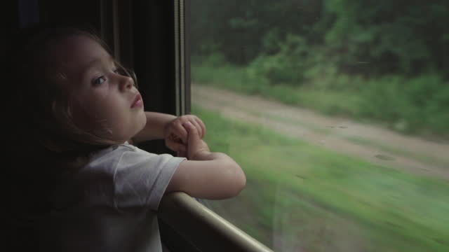 Portrait of cute little girl looking out the window of a leading train.