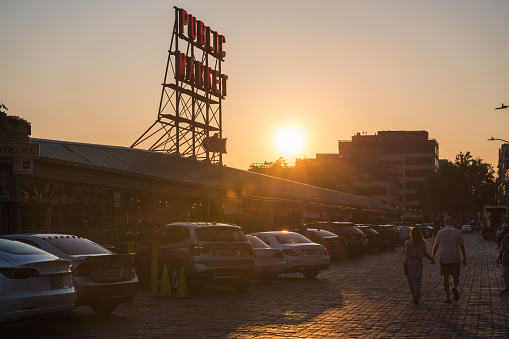 Seattle, USA - Jul 3, 2021: Late in the day People enjoying the summer as the setting sun passes the iconic public market sign at Pike Place Market.