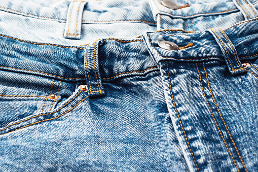 Close-up of the denim pockets, seams. Elements of denim clothing. Jeans background for sewing. Natural, durable denim fabrics.