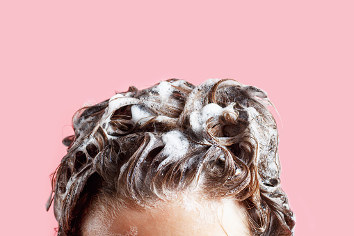 Fmale champú para el cabello y espuma en primer plano de fondo rosa. photo