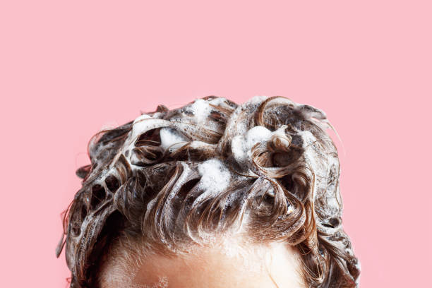 shampoo per capelli fmale e schiuma su sfondo rosa da vicino. - wash stand foto e immagini stock