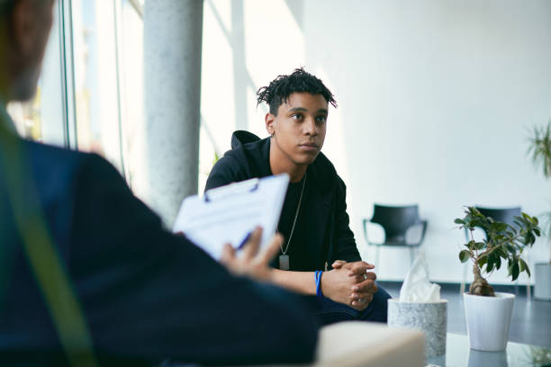 African American teenager having psychotherapy session at psychologist's office. Black teenage boy having counselling with mental health professional during therapy session. counseling stock pictures, royalty-free photos & images