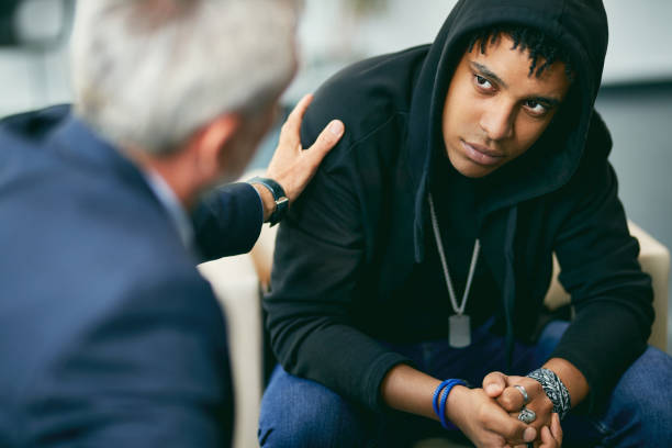 psicoterapeuta maduro que anima al adolescente masculino negro durante terapia en el centro de asesoramiento. - mental health professional psychiatrist therapy teenager fotografías e imágenes de stock