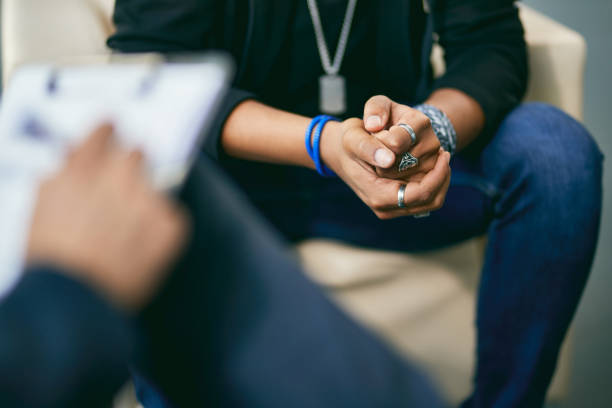 Close-up of black adolescent having a therapy session with psychologist. Close-up of African American teenage boy having a session with mental health professional at counselling center. young black boys stock pictures, royalty-free photos & images
