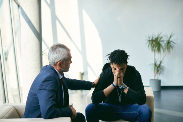 depressiver afroamerikanischer teenager bei einem treffen mit seinem therapeuten im psychotherapiezentrum. - mental health professional psychiatrist therapy teenager stock-fotos und bilder