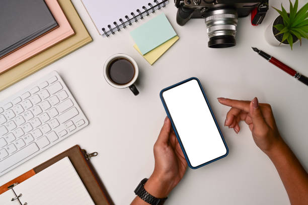 istock Overhead shot woman using mobile phone on white office desk. 1331030683