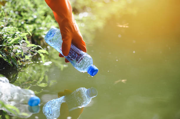 istock Man handpicking gathering up garbage plastic bottle garbage from the river at the park. World environment day.Environment concept. 1331030729