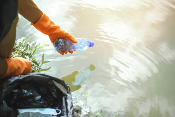 istock .Man handpicking gathering up garbage plastic bottle garbage from the river at the park. World environment day.Environment concept. 1331030736